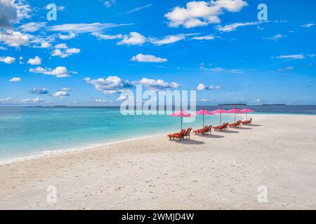 Fantastischer Blick aus der Luft auf die paradiesische Strandlandschaft mit Liegestühlen und rosa Sonnenschirmen in der Nähe des fantastischen tropischen Meeres. Weißer Sand und blaues kristallklares Meer Stockfoto