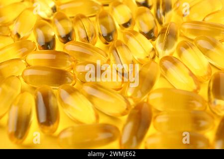 Viele Vitaminkapseln auf gelbem Hintergrund, Nahaufnahme Stockfoto