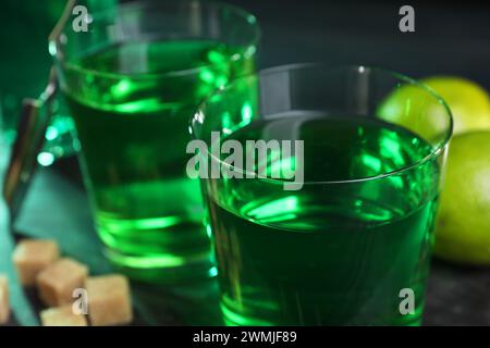 Absinth in Gläsern, brauner Zucker und Limette auf dem Tisch, Nahaufnahme. Alkoholisches Getränk Stockfoto