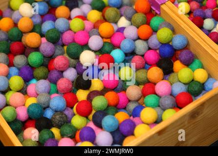 Bunte Kugeln, die aus einer Holzkiste überlaufen, wie Ein Regenbogen der Freude Stockfoto