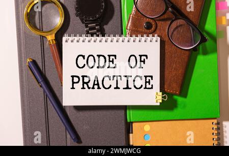 Code of Practice Text auf einem Notizbuch mit Bleistiften geschrieben. Stockfoto