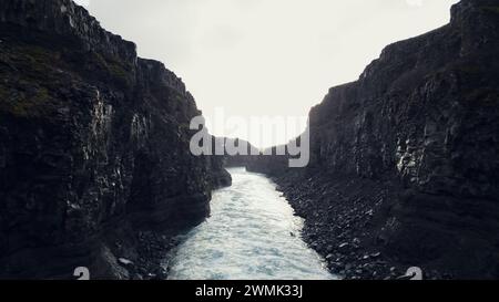 Blick aus der Vogelperspektive auf den majestätischen Wasserfall in island, Fluss fließt von Hügeln mit gefrorenen Feldern und Landschaften hinunter. Fantastische isländische Natur mit einem Wasserstrom, Canyonfelsen. Zeitlupe. Stockfoto