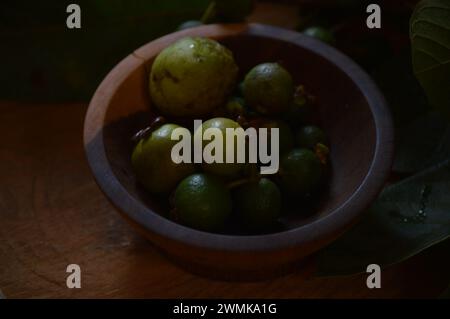 Araçá- oder Cattley-Guave-Frucht mit wissenschaftlichem Namen (Psidium Cattleianum) in rustikaler Holzschale Stockfoto