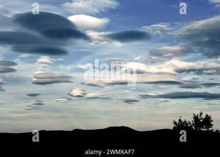 Lentikularwolken bilden sich über Bergen. Antikrepuskuläre Strahlen steigen auf, um sie zu treffen. Stockfoto