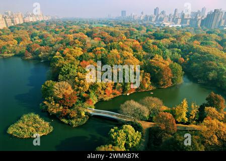 Blick aus der Vogelperspektive nördlich des Central Park und der Skyline von Manhattan im Herbst. Die Bow Bridge überquert den See zum Bramble Stockfoto