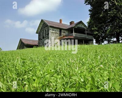 Verlassenes Bauernhaus auf einem grasbewachsenen Hügel mit blauem Himmel im westlichen North Carolina; North Carolina, Vereinigte Staaten von Amerika Stockfoto