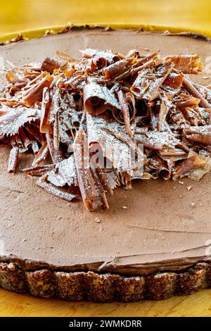 Nahaufnahme eines Schokoladen-Mousse-Pie mit Krustenboden auf einem hölzernen Schneidebrett und Glasur mit Schokolade darüber; Studio Stockfoto