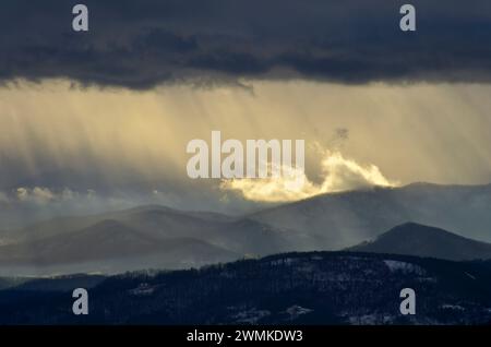 Sonnenlicht strömt durch Sturmwolken über die Blue Ridge Mountains in der Dämmerung; North Carolina, Vereinigte Staaten von Amerika Stockfoto