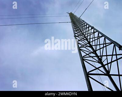 Gitterturm und elektrische Leitungen bei bewölktem Himmel Stockfoto