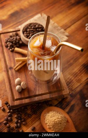 Eiskaffee serviert in einer doppelwandigen Glasschale und Metallstroh, ein kaltes Sommergetränk mit Eiswürfeln und Gewürzen, Zimt, Muskatnuss, Vanille, Mu Stockfoto