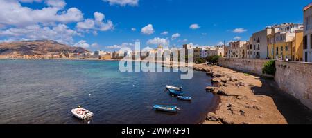 Kleine Boote, die am Ufer der Skyline von Trapani mit alten Steinbauten und einer Meeresmauer vor Anker liegen; Trapani, Sizilien, Italien Stockfoto