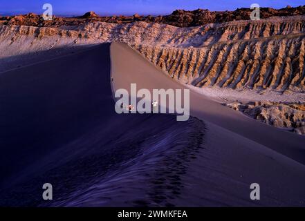 Wanderer, die auf dem Gipfel einer großen Düne in der Atacama-Wüste spazieren, einer Region im Norden Chiles, die als der trockenste Ort der Erde gilt. Loca... Stockfoto