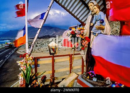 Flaggen und Statuen schmücken einen farbenfrohen Altar am Straßenrand in einer einsamen Region im Norden Chiles. Schreine oder Aniitas sind eine gängige Tradition der Erinnerung... Stockfoto