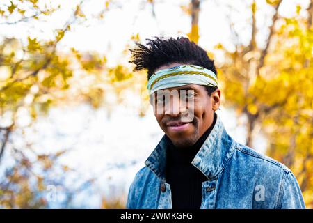 Nahaufnahme eines hübschen Mannes mit Kopfband, der im Herbst in einem Stadtpark in Edmonton, Alberta, Kanada, in die Kamera blickt Stockfoto