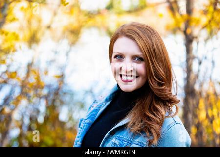 Nahaufnahme eines Porträts einer schönen Frau, die während eines Herbstausflugs in einem Stadtpark für die Kamera posiert; Edmonton, Alberta, Kanada Stockfoto