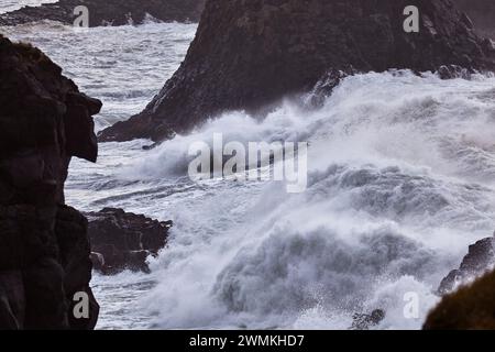 Sturmsurfen entlang einer zerklüfteten Küste mit schwarzem Felsen auf Arnastapi, der Halbinsel Snaefellsnes, der Westküste Islands und Island Stockfoto