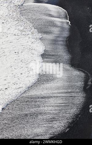 Wasserstrukturen treffen auf Sand, während die Brandung an einem schwarzen Sandstrand im Süden Islands auf Dyrholaey Island in der Nähe von Vik auftaucht Stockfoto