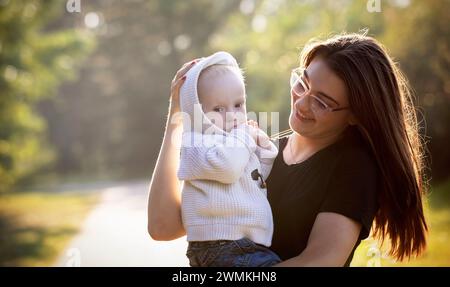 Außenporträt einer älteren Schwester, die an einem warmen Herbstnachmittag mit ihrem kleinen Bruder, der an dem Down-Syndrom leidet, in einem Stadtpark Zeit verbringt Stockfoto