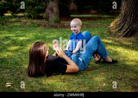 Die ältere Schwester verbringt an einem warmen Herbstnachmittag Zeit mit ihrem jungen Bruder, der an einem Down-Syndrom leidet, in einem Stadtpark; Leduc, Alberta, Kanada Stockfoto