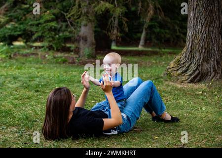 Die ältere Schwester verbringt an einem warmen Herbstnachmittag Zeit mit ihrem jungen Bruder, der an einem Down-Syndrom leidet, in einem Stadtpark; Leduc, Alberta, Kanada Stockfoto