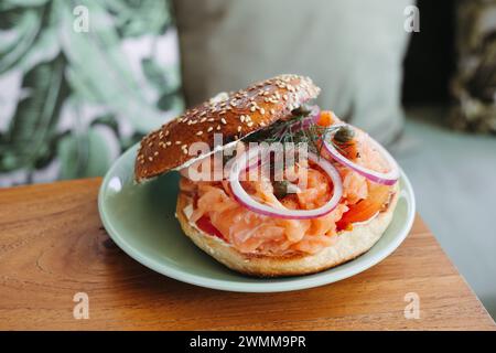 Nahaufnahme eines Bagel mit Räucherlachs, roter Zwiebeln und Kapern auf einer grünen Platte Stockfoto