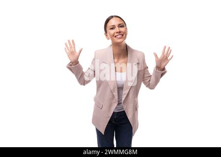 Die junge positive weiße Frau mit einem Pferdeschwanz in einer Jacke lacht auf weißem Hintergrund Stockfoto