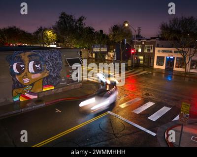 LOS ANGELES, CA - 5. Februar 2024: Verkehr an der Kreuzung von Santa Monica Blvd und N Genesee Ave in West Hollywood, mit süßen Graffiti Stockfoto