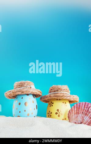 Gelbe und blaue Eier mit Polka Dot im Hut mit Muschel am Strand am Meer an sonnigen Tagen. Ostern, Reisen, Urlaub. Vertikal. Kopierbereich Stockfoto