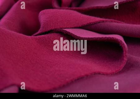 Lagen aus französischem Frottee-rosa Amaranth-Textil auf der Vorder- und Rückseite. Ein Stück Stoff liegt in wunderschönen Wellen. Schnitt zum Nähen. Hintergrund des magentafarbenen Materials. Polycotton Cotton Poly Stockfoto