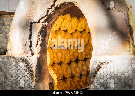 Usbekische Fladenbrote aus rohem Teig werden in einem heißen Tandoor gebacken. Die nationale Küche Usbekistans. Der Prozess der Brotbackherstellung im Ofen. Stockfoto