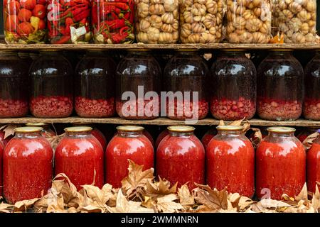 Hauskompott auf Holzbrettern. Natürliche Getränke auf einem alten Holzregal. Säfte in Dosen im Keller. Stockfoto