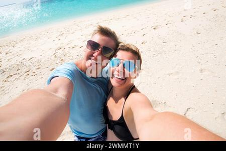 Schönes glückliches lächelndes Paar, das Selfie am Strand macht, Vorderansicht Stockfoto