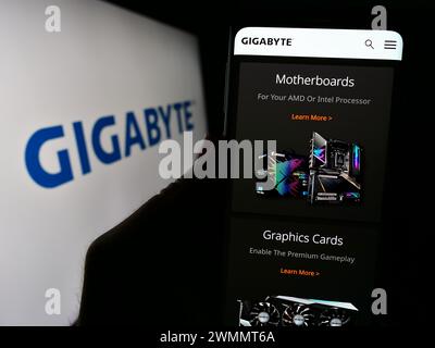 Person, die ein Mobiltelefon mit Webseite des taiwanesischen Computerhardware-Unternehmens Gigabyte Technology mit Logo hält. Konzentrieren Sie sich auf die Mitte des Telefondisplays. Stockfoto