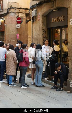 Barcelona, Spanien - 27. Februar 2024: Eine Gruppe von Menschen wartet geduldig vor dem Joncake-Laden, um einen alltäglichen urbanen Moment festzuhalten. Stockfoto