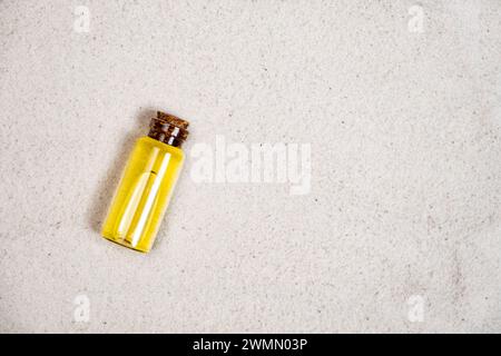 Ätherisches Öl in Glasflasche auf Sand, Draufsicht, Platz für Text. Stockfoto