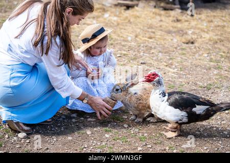 Mutter und kleine Tochter füttern Kaninchen und Vögel auf der Farm Stockfoto