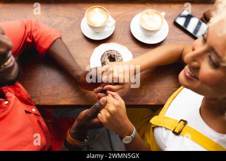 Ein afroamerikanischer Mann macht sich einen Antrag auf eine Frau in einem gemütlichen Café Stockfoto