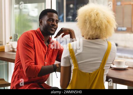Ein junger afroamerikanischer Mann plaudert mit einer jungen Frau in einem Café Stockfoto