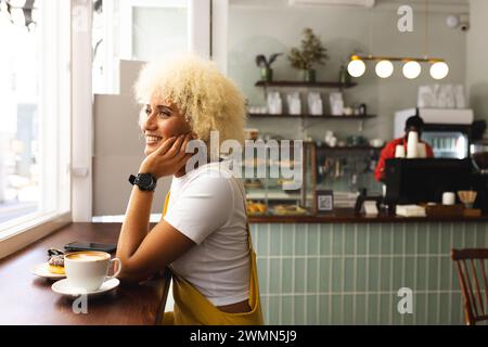 Eine junge birassische Frau genießt einen Kaffee in einem gemütlichen Café mit Kopierraum Stockfoto