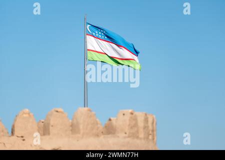 Oberste Seite der Mauern der Festung Ichan-Kala (historische Innenstadt) und die Nationalflagge Usbekistans über der Stadt. Beeindruckender Spaziergang auf dem Zitadellwal Stockfoto