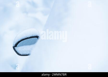 Ein Seitenspiegel von Autos ist von einer Decke aus frischem Schnee umgeben und spiegelt die kühle Winteratmosphäre in Schweden wider. Das Fahrzeug scheint stillstehend und beschichtet zu sein Stockfoto