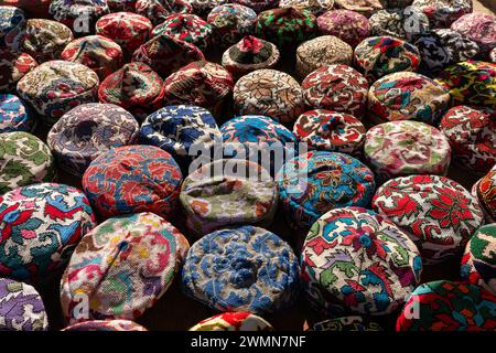 Eine Menge farbenfroher, schöner Schädelkappen auf einem Tisch auf einem Straßenbasar in der Altstadt von Chiwa, Chorezm Region, Usbekistan. Stockfoto