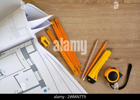 Architekturzeichnungen und Bleistifte, Lineal, Maßband, klerikales Messer auf hölzernem Hintergrund. Draufsicht. Gehäusekonzept reparieren. Stockfoto