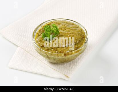 Basilikumpesto in Glasschale auf weißer Serviette Stockfoto