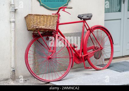 Rotes Fahrrad. Historisches Fahrrad mit Korb an einer Wand. Stockfoto