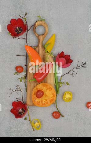 Zusammensetzung von Gemüse, Ästen und Blumen auf Marmortisch. Essen ist Kunst, Abstraktion. Stockfoto