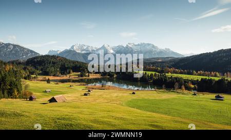 Geroldsee im Alpental bei Gerold Stadt an einem sonnigen Herbsttag: Kleine Holzscheune auf grüner Wiese und dahinter verschneite Karwendelgebirge. Stockfoto