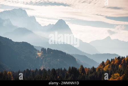 Bergsilhouetten im Dunst an einem sonnigen Tag in Bayern: Waldbedeckte Mittelgebirge vor felsigen Berggipfeln. Stockfoto