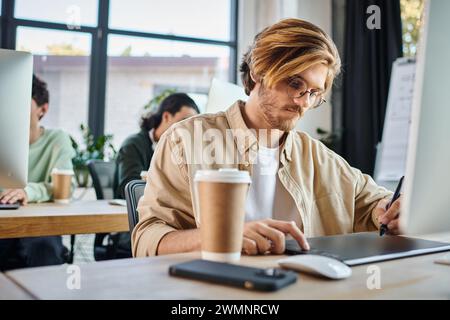 Fokussierter Mann, der an kreativen Projekten arbeitet und sein Tablet im Coworking- und Retuschierteam von Startup verwendet Stockfoto