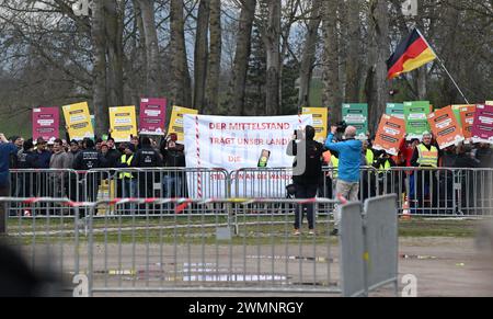 Freiburg, Deutschland. Februar 2024. Demonstranten stehen mit Spruchbändern vor Barrieren bei einer Festveranstaltung zum Spatenstich für den großen neuen Stadtteil Dietenbach in Freiburg. Quelle: Bernd Weißbrod/dpa/Alamy Live News Stockfoto